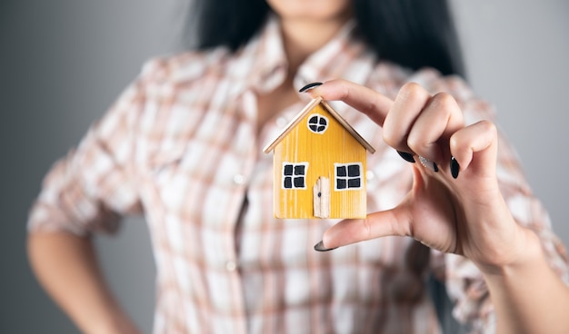 Mujer sosteniendo y mostrando el modelo de casa de madera