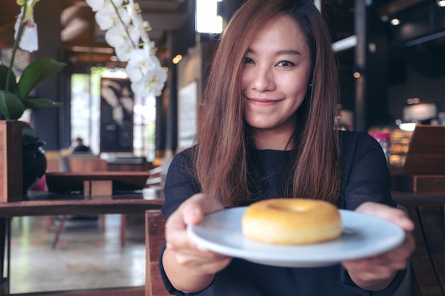 Una mujer sosteniendo y mostrando un plato de donut.