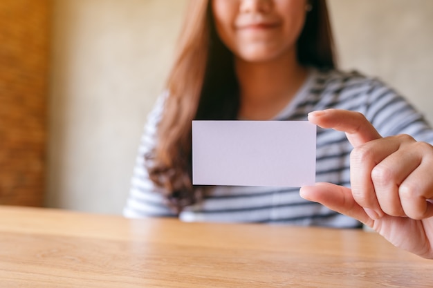 Foto una mujer sosteniendo y mostrando una tarjeta de presentación vacía en blanco