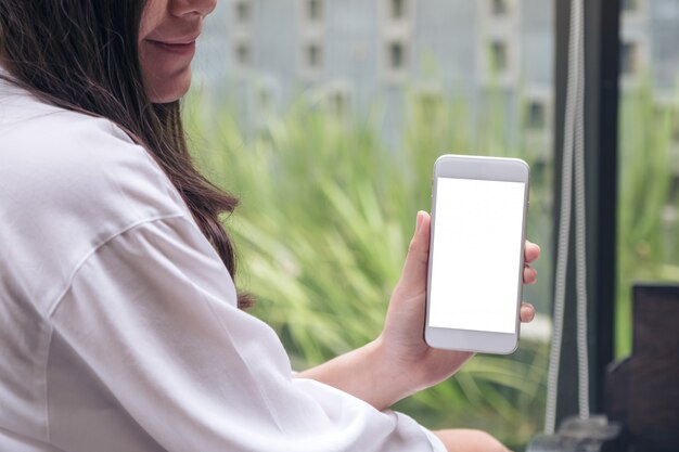 Mujer sosteniendo y mostrando teléfono móvil blanco