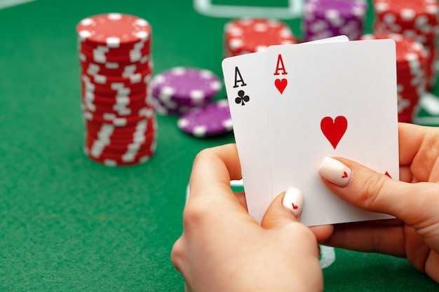 Mujer sosteniendo naipes jugando al póquer en la mesa verde