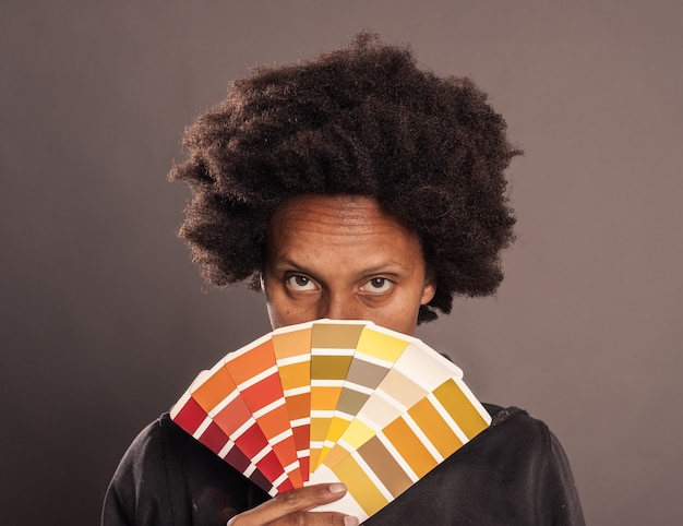 Foto mujer sosteniendo una paleta de colores en un gris