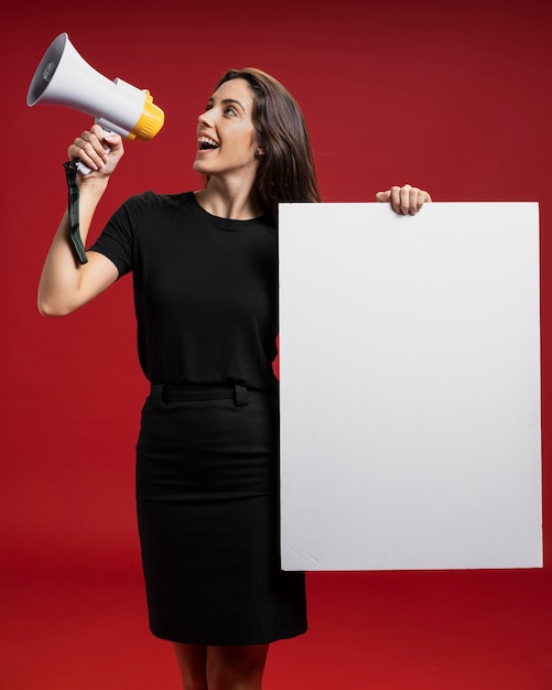 Foto mujer sosteniendo una pancarta vacía mientras gritaba en un megáfono