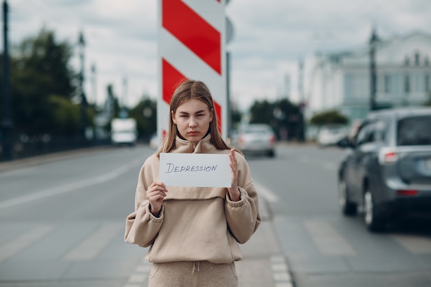 Mujer sosteniendo papel blanco etiquetado palabra depresión en la mano.