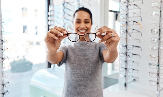 Mujer sosteniendo un par de gafas nuevas de moda, gafas elegantes y lentes recetados en un optometrista Retrato de un cliente que elige comprar y comprar marcos para una mejor visión y vista