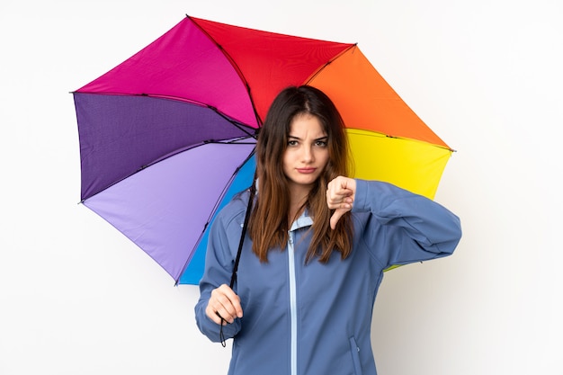 Mujer sosteniendo un paraguas en la pared blanca que muestra el pulgar hacia abajo