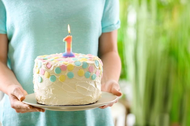 Mujer sosteniendo pastel con velas para el primer cumpleaños de primer plano