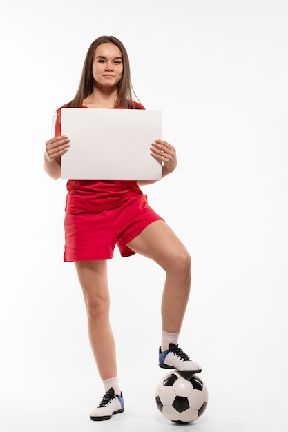 Mujer sosteniendo una pelota de fútbol y un portátil