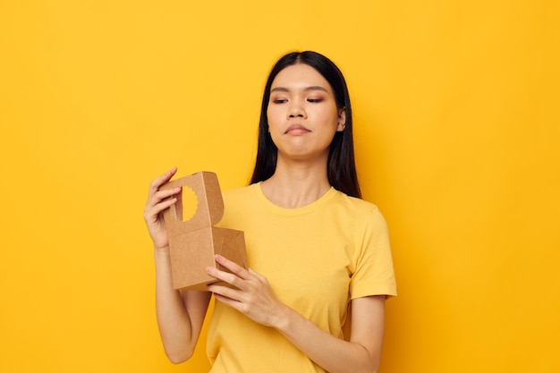 Mujer sosteniendo una pequeña caja de regalo fondo amarillo