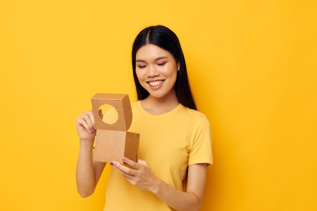 Mujer sosteniendo una pequeña caja de regalo fondo amarillo