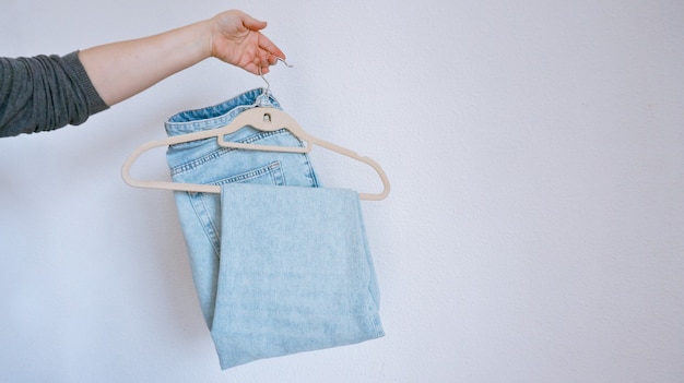 mujer sosteniendo una percha con blue jeans