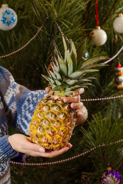 Mujer sosteniendo piña con árbol de Navidad en el fondo