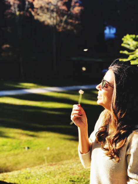 Foto mujer sosteniendo una planta en un día soleado