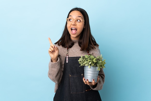 mujer sosteniendo una planta con la intención de darse cuenta de la solución mientras levanta un dedo