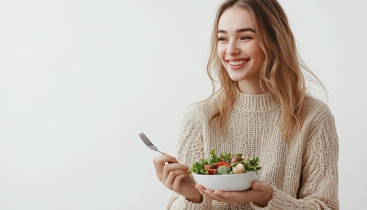 una mujer sosteniendo un plato de ensalada con un cuchillo y un tenedor