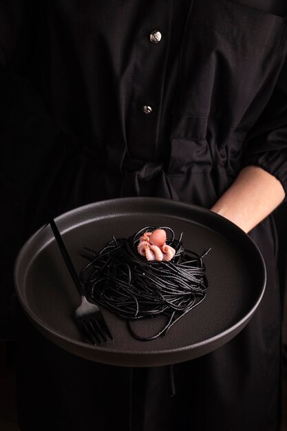 Foto mujer sosteniendo un plato con espagueti con tinta de sepia y pulpo