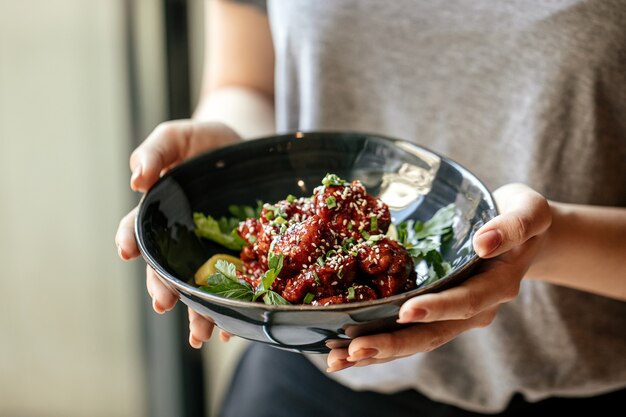 Mujer sosteniendo un plato de pollo marinado en salsa picante con daikon