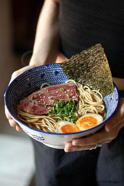 Foto mujer sosteniendo un plato de sopa de fideos ramen