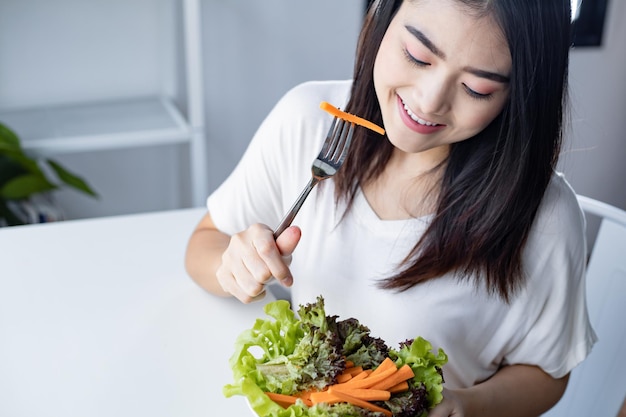 Mujer sosteniendo un plato de verduras para una dieta saludable con una sonrisa en el cuidado de la salud. Hermosa mujer sonriente comiendo ensalada vegetariana orgánica fresca. Mujer joven comiendo ensalada saludable en concepto de dieta.