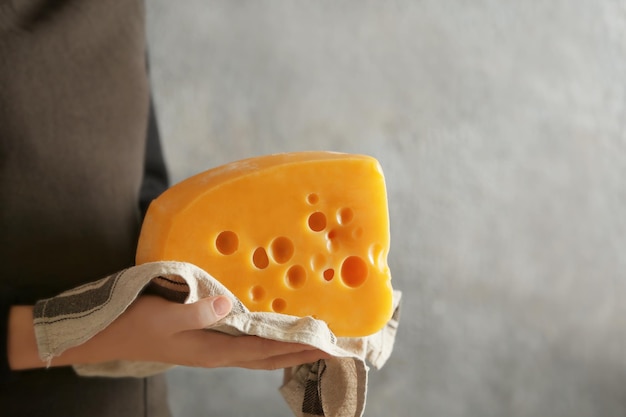 Mujer sosteniendo queso en lonchas sobre fondo gris