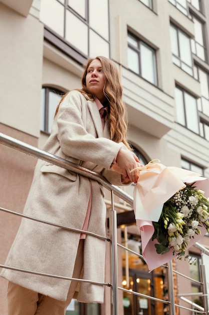 Mujer sosteniendo ramo de flores al aire libre en la ciudad