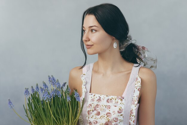 Mujer sosteniendo ramo de flores en manos sobre fondo gris