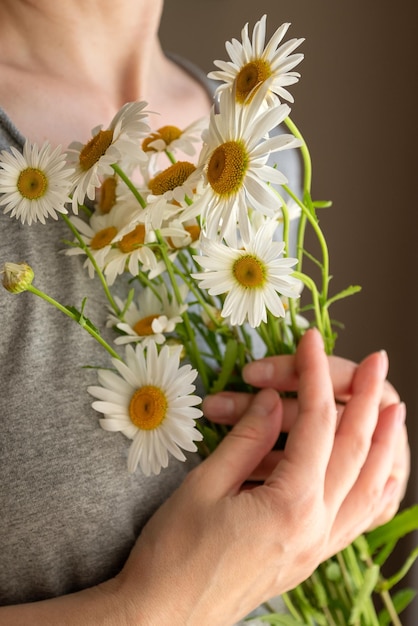 Mujer sosteniendo un ramo de flores de manzanilla blanca en sus manos