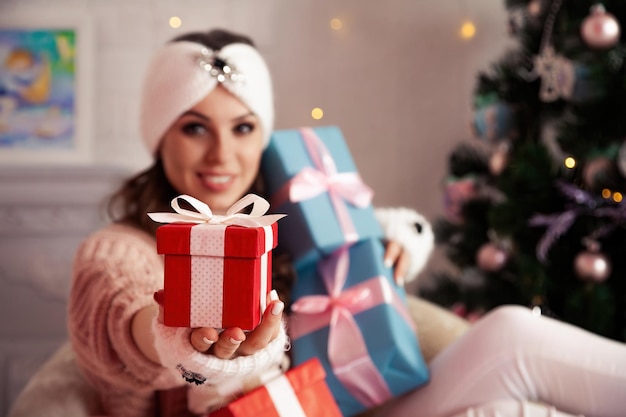 Mujer sosteniendo un regalo de Navidad Hermosa mujer alegre da un regalo rojo sobre un fondo