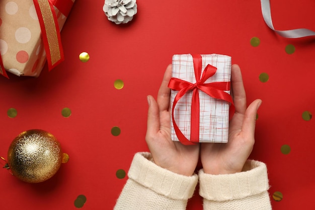 Mujer sosteniendo regalo de Navidad en la vista superior de fondo rojo