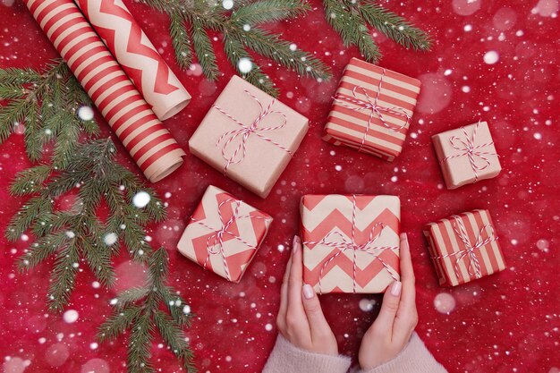 Mujer sosteniendo regalos de Navidad en un fondo de mesa rojo...