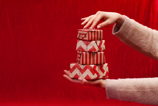 Foto mujer sosteniendo regalos de navidad en un fondo de mesa rojo...