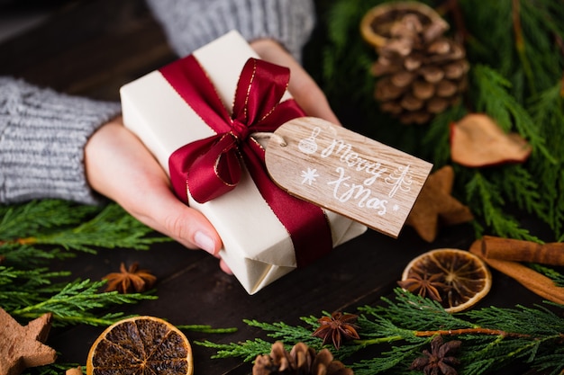 Mujer sosteniendo regalos de Navidad sobre un fondo de mesa de madera.