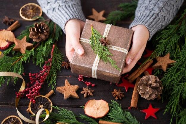 Mujer sosteniendo regalos de Navidad sobre un fondo de mesa de madera.