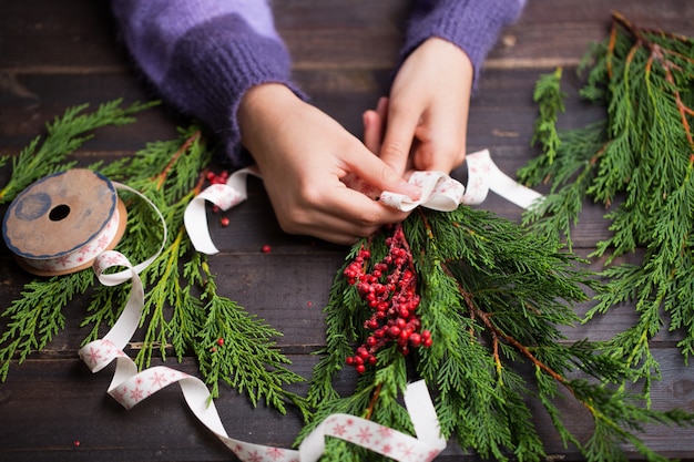 Mujer sosteniendo regalos de Navidad sobre un fondo de mesa de madera.