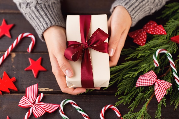 Mujer sosteniendo regalos de Navidad sobre un fondo de mesa de madera.