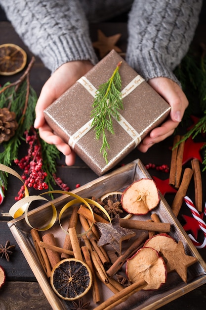 Mujer sosteniendo regalos de Navidad sobre una mesa de madera.