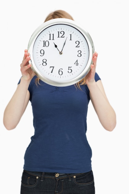 Mujer sosteniendo un reloj frente a su cara