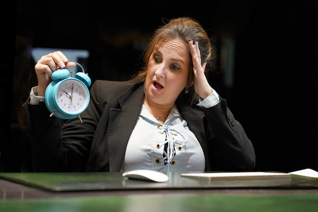 Foto mujer sosteniendo un reloj. la mujer sostiene un despertador en la mano en el lugar de trabajo.