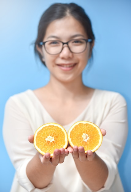 Mujer sosteniendo rodajas de naranja.