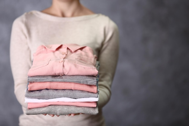 Mujer sosteniendo ropa lavada y seca sobre fondo gris