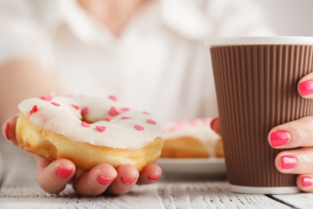 Mujer sosteniendo una rosquilla rosa