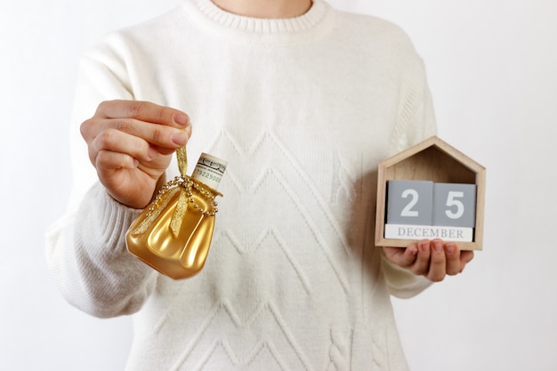 Mujer sosteniendo saco de regalo de Navidad con dólar y calendario