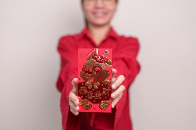 Mujer sosteniendo un sobre rojo chino con un conejo dorado y una palabra de bendición regalo de dinero para las felices vacaciones del Año Nuevo Lunar La oración china significa felicidad saludable Afortunado y rico