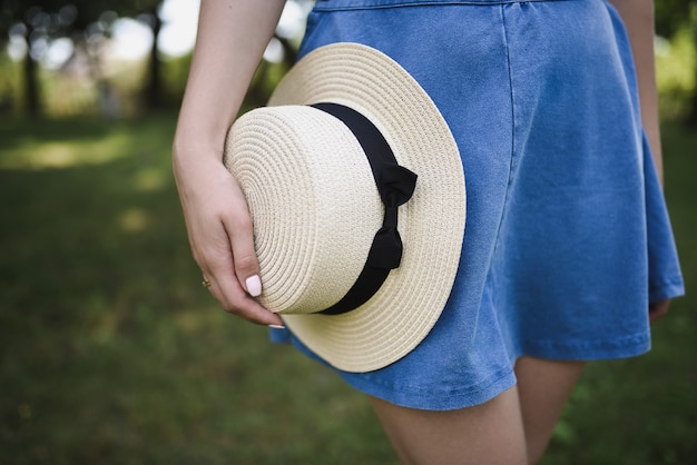 Mujer sosteniendo sombrero de canotier en el parque