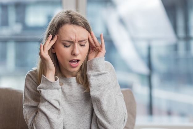 una mujer sosteniendo su cabeza ansiosa por un dolor de cabeza insoportable