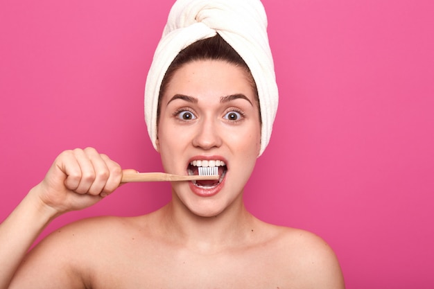 Mujer sosteniendo su cepillo de dientes de madera en la cavidad, haciendo el procedimiento diario, disfrutando el proceso, cuidando su salud