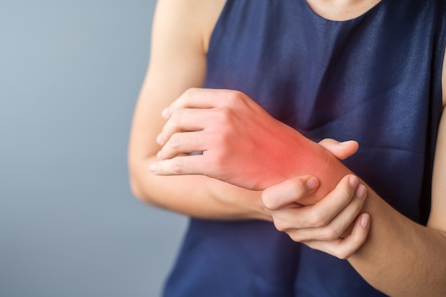 Mujer sosteniendo su dolor de muñeca porque usa un teléfono inteligente o una computadora durante mucho tiempo. Tenosinovitis de De Quervain, síntoma de intersección, síndrome del túnel carpiano o concepto de síndrome de Office