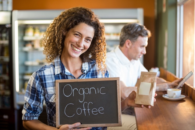 Mujer sosteniendo un tablero que lee café orgánico