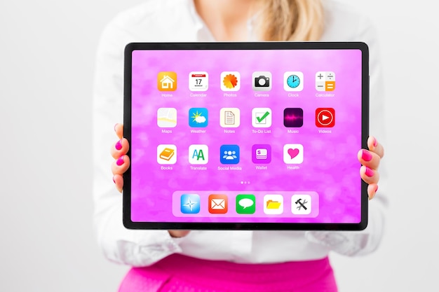 Mujer sosteniendo una tableta con iconos de aplicaciones de pantalla de inicio de muestra