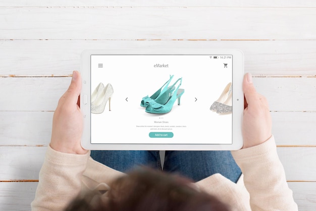 Foto mujer sosteniendo una tableta y usando la aplicación de comercio electrónico para encontrar zapatos nuevos vista superior sobre la cabeza